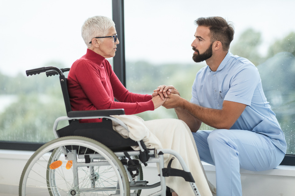 A care attendant supporting a senior patient in a wheelchair